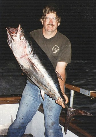 Peter holding a 45-lb bluefin tuna at night