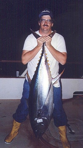 Peter holding a 5-foot-long  yellowfin tuna by the tail